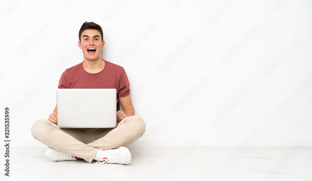 Teenager man sitting on the flor with his laptop with surprise facial expression Teenager man sitting on the flor with his laptop with surprise facial expression