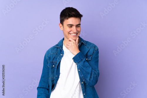 Teenager caucasian handsome man isolated on purple background looking to the side