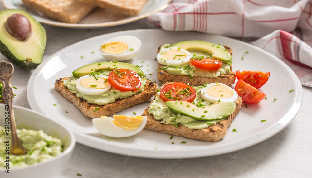 Healthy breakfast from toasts with avocado spread guacamole egg tomato and chives. Healthy breakfast from toasts with avocado spread guacamole egg tomato and chives.