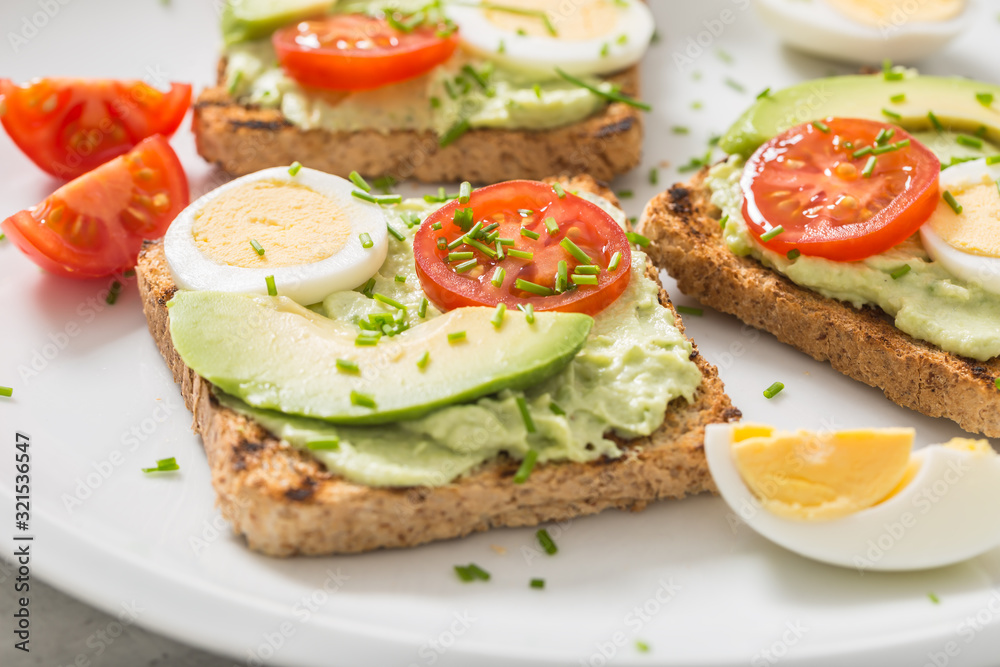 Healthy breakfast from toasts with avocado spread guacamole egg tomato and chives.