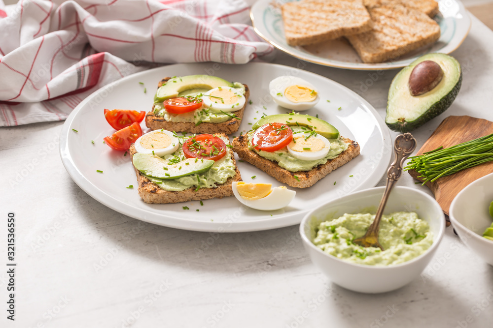 Healthy breakfast from toasts with avocado spread guacamole egg tomato and chives.