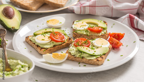 Healthy breakfast from toasts with avocado spread guacamole egg tomato and chives.