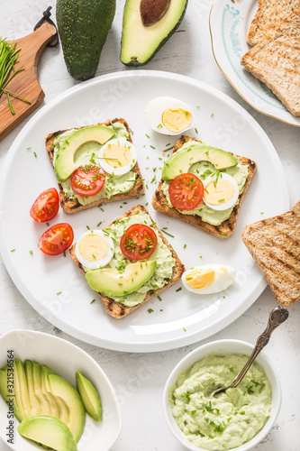 Healthy breakfast from toasts with avocado spread guacamole egg tomato and chives.