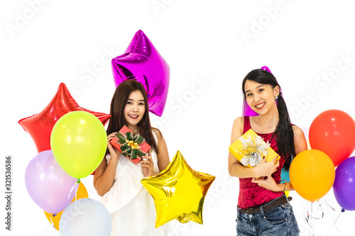 Two young asian girls holding present box with many colourful balloons in front of white background.