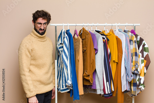 young cool berded man with clothes against flat wall photo