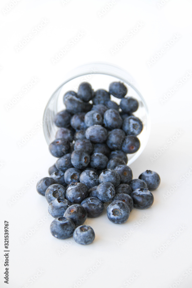 Fresh blueberries in a small glass on a white background. Healthy eating. Vegan food. Back view. Fresh blueberries in a small glass on a white background. Healthy eating. Vegan food. Back view.