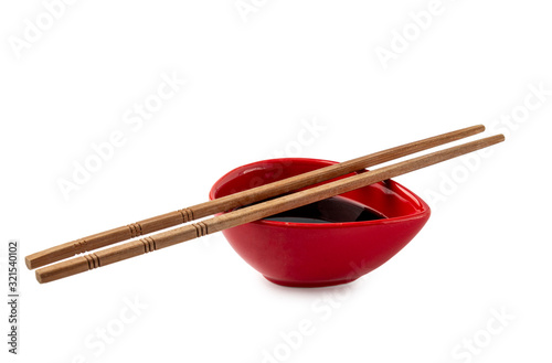 Soy sauce in red dish with chopsticks isolated on white background.
