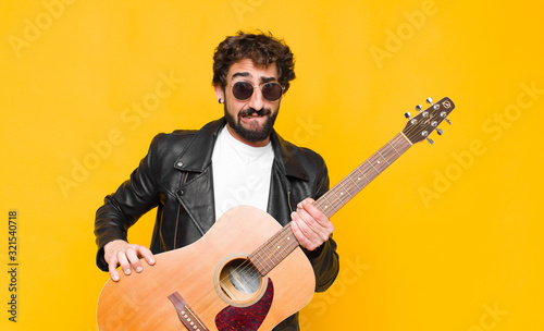 young musician man feeling clueless, confused and uncertain about which option to pick, trying to solve the problem with a guitar, rock and roll concept photo