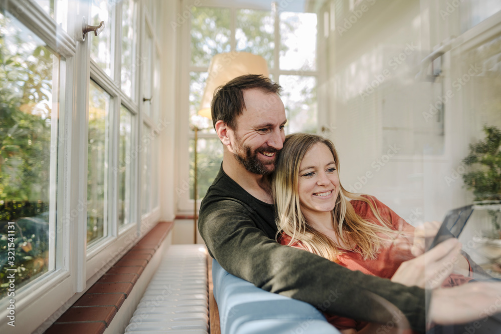 Happy couple relaxing on couch, using smartphone Happy couple relaxing on couch, using smartphone