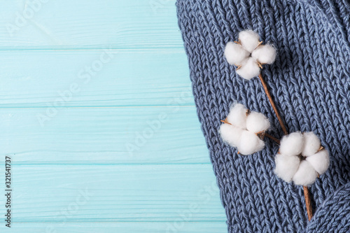 cotton flower on a knitted plaid, gray plaid with large knitting on a blue background