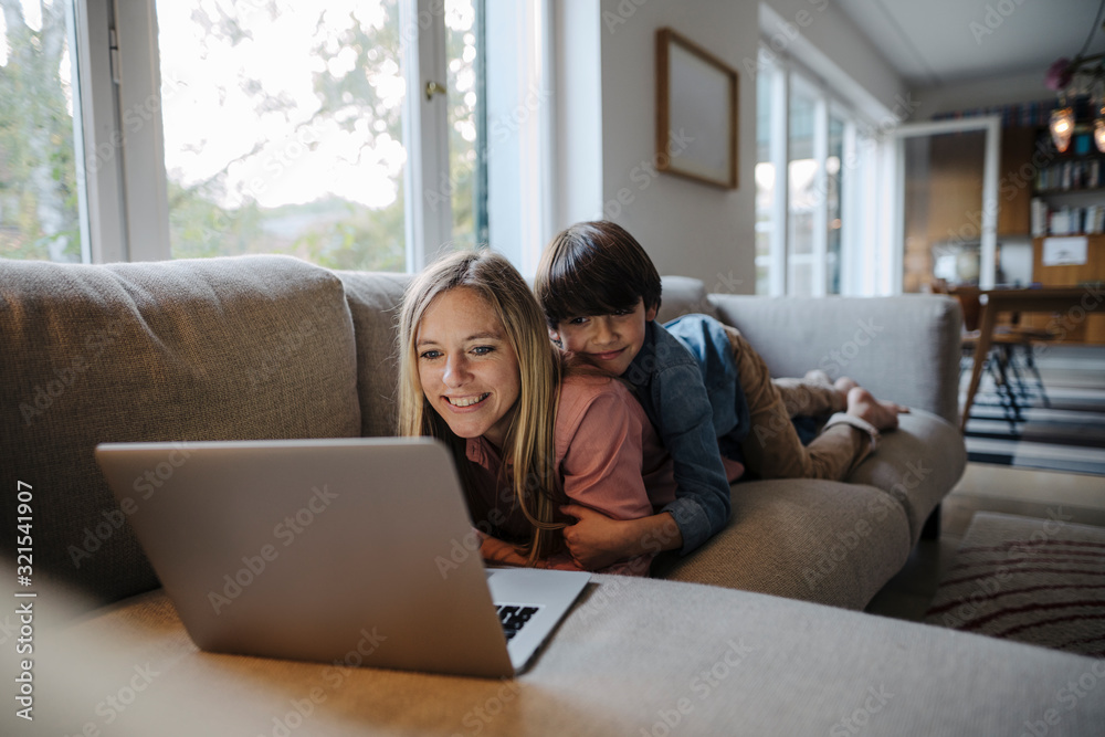 Mother and son lying on couch, using laptop Mother and son lying on couch, using laptop