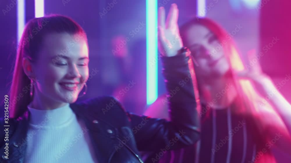 Neon women. Party lifestyle. Amused teen girls enjoying dancing in purple lights. Neon women. Party lifestyle. Amused teen girls enjoying dancing in purple lights.