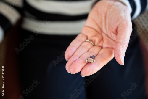Senior woman's hand with modern hearing aid