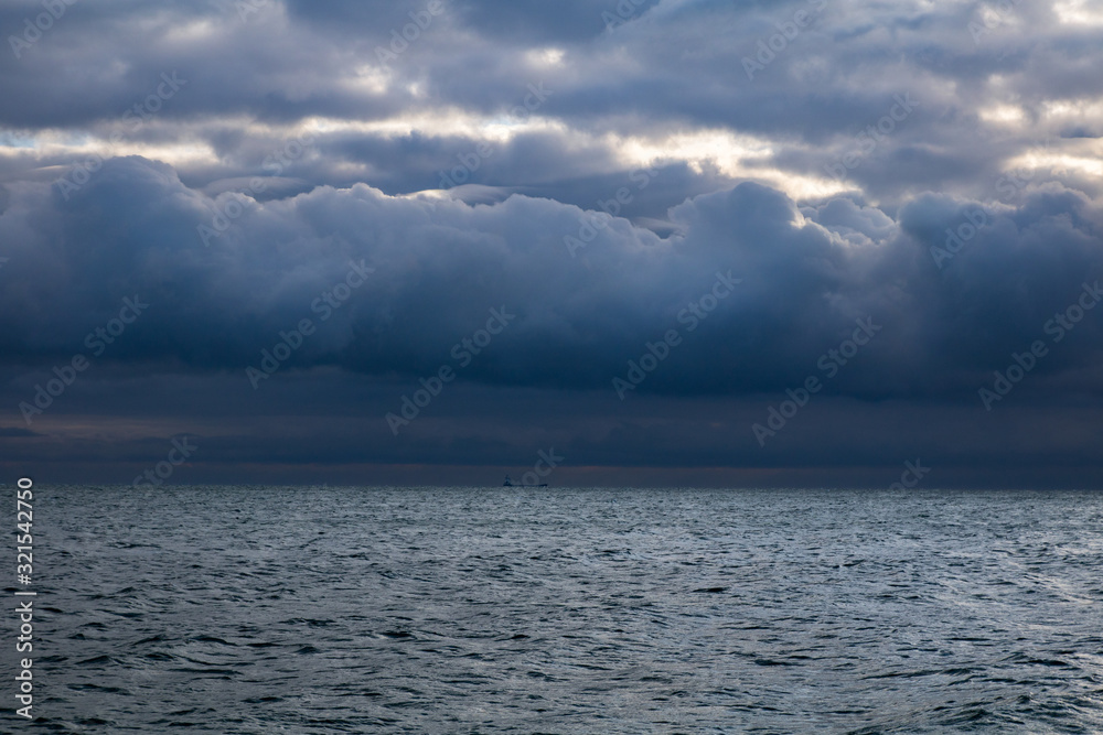 Fototapeta premium blue dark stormy clouds above the sea and ship on the horizon