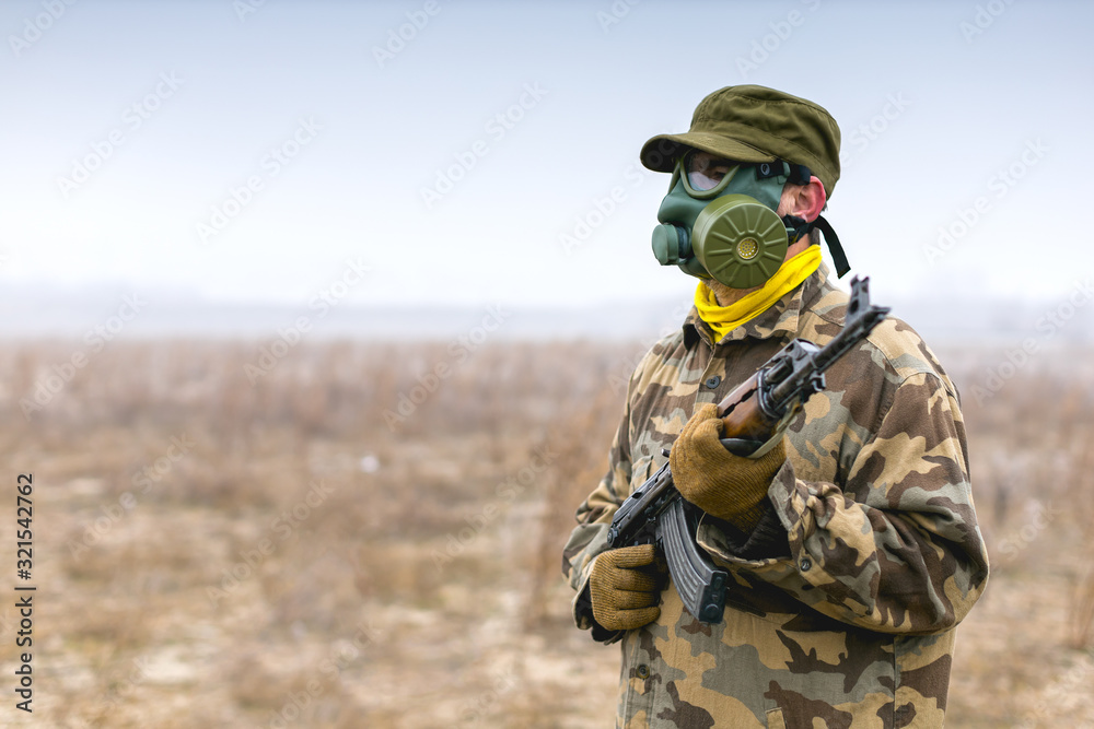 Soldier with gas mask and automatic gun standing ready