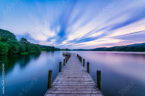 UK, England, Long exposure of clouds over jetty on Coniston Water lake at dusk