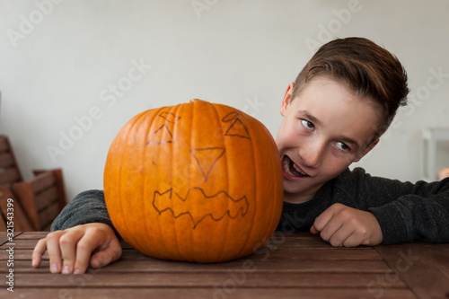 Boy making a face beside big Halloween pumpkin photo