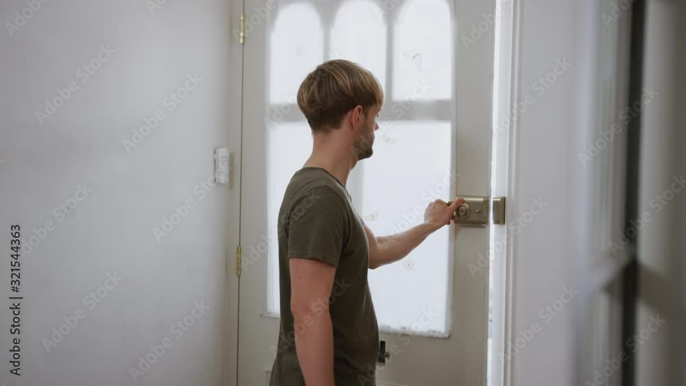 Same Sex Male Couple With Baby Daughter In Sling Opening Front Door Of Home Same Sex Male Couple With Baby Daughter In Sling Opening Front Door Of Home