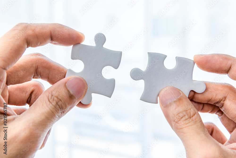 Hand holding two pieces of jigsaw connecting couple puzzle Hand holding two pieces of jigsaw connecting couple puzzle