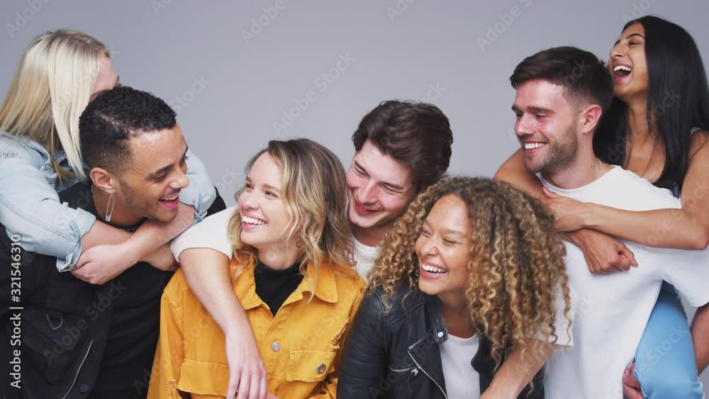 Group Studio Shot Of Young Multi-Cultural Friends Smiling And Laughing At Camera In Slow Motion Group Studio Shot Of Young Multi-Cultural Friends Smiling And Laughing At Camera In Slow Motion