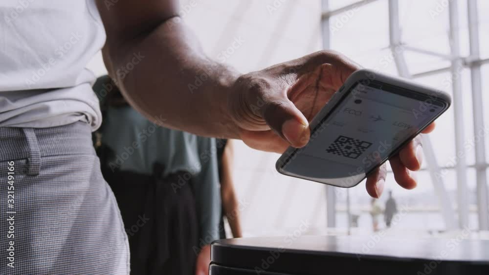 Close Up Of Businessman In Airport Departure Lounge Scanning E-Ticket On Mobile Phone 