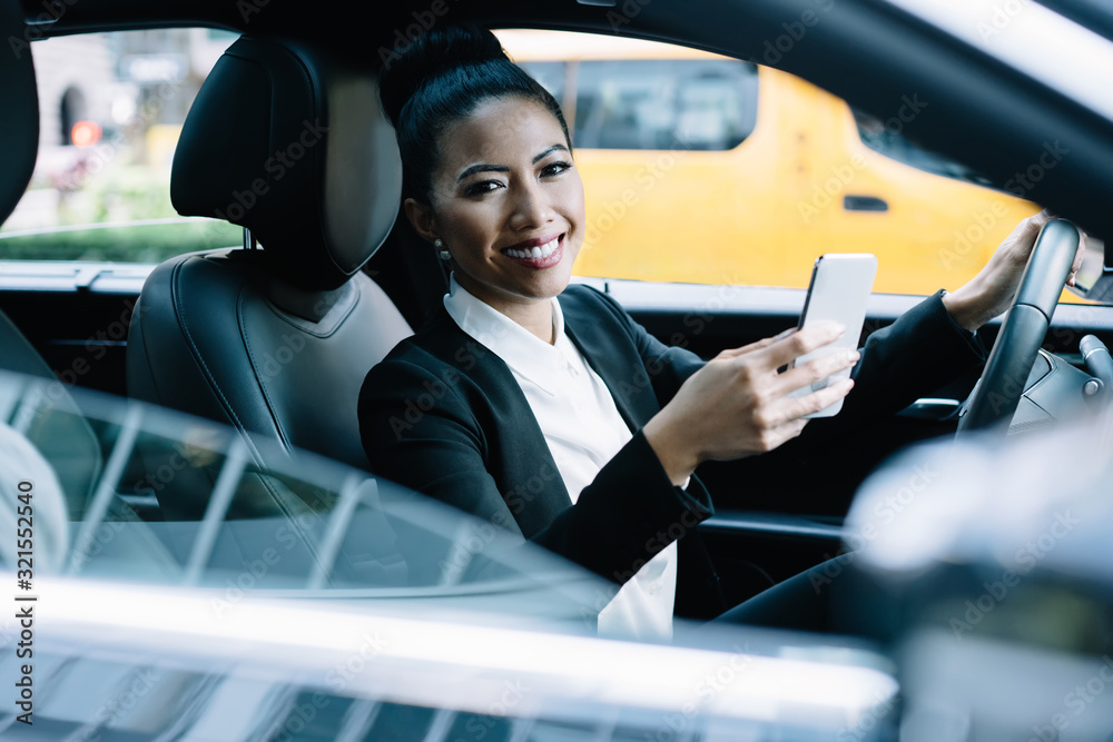 Optimistic entrepreneur driving car watching phone