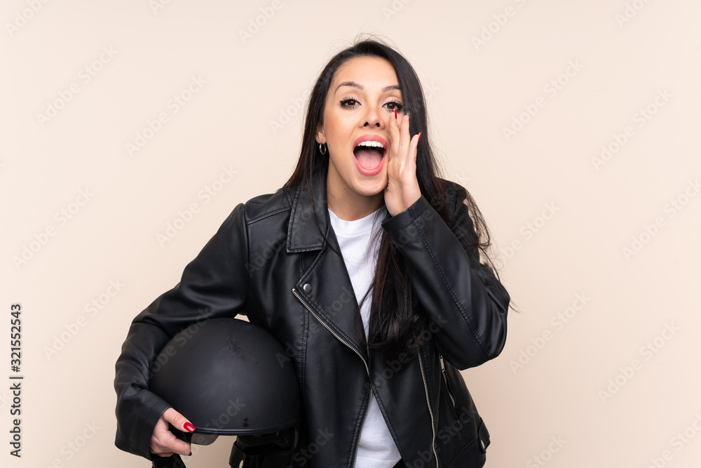 Young Colombian girl holding a motorcycle helmet over isolated background shouting with mouth wide open Young Colombian girl holding a motorcycle helmet over isolated background shouting with mouth wide open