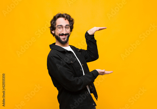Canvas Print young crazy handsome man smiling, feeling happy, positive and satisfied, holding