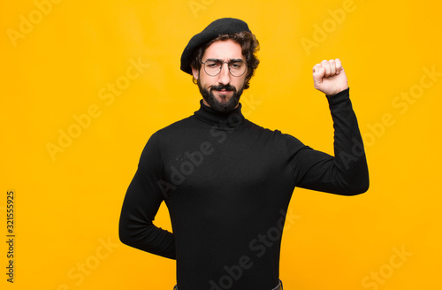 Photography young french artist man feeling serious, strong and rebellious, raising fist up,