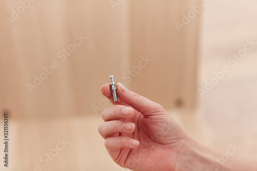 A woman s hand  holding a screw for furniture assembly. Concept for self-contained  easy furniture assembly.