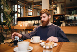 Young handsome bearded man having coffee break in cafe