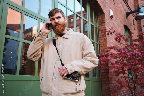 Young bearded man angrily talking on cellphone outdoor