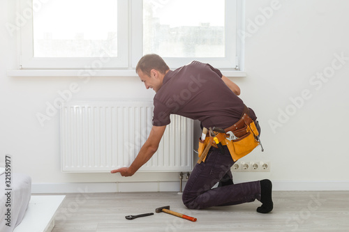 Фотография Man is repairing radiator battery in the room