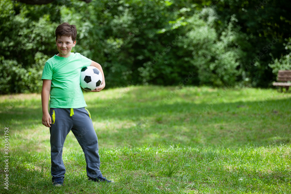 Teen child soccer player. Football Boy with ball on green grass.