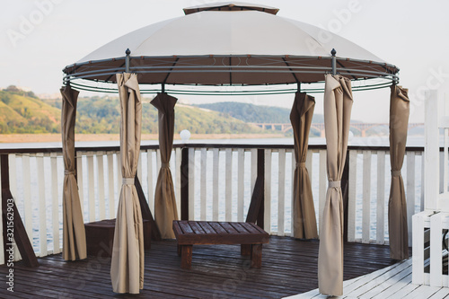 Beautiful modern marquee on the terrace of the landing stage. Natural wood. View of the river and mountains.