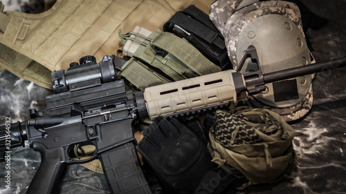 Close up of equipment carried by a Military Contractor featuring an AR15, ammunition, gloves, and body armor.