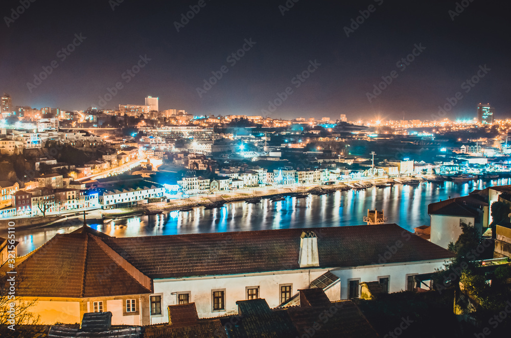 Porto and Vila Nova de Gaia top view at night. Illuminated old buildings reflected on water of the Douro river