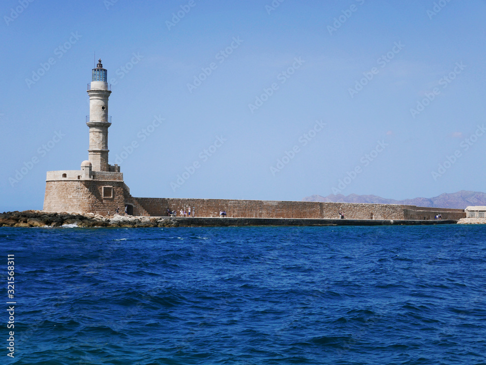 Lighthouse on the sea coast with blue sea and sky with copy space. Summer holidays on Crete in Chania. Travel and relax.