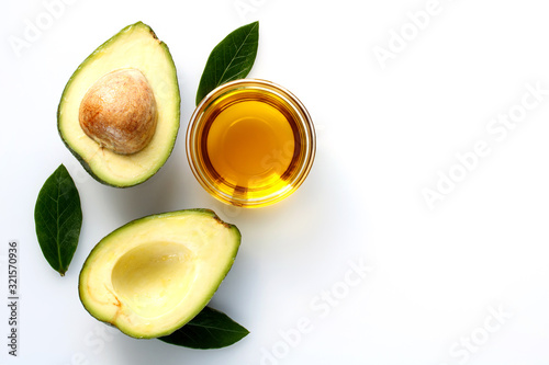 Avocado oil and halves of raw avocado for a healthy diet and body care on a white background.