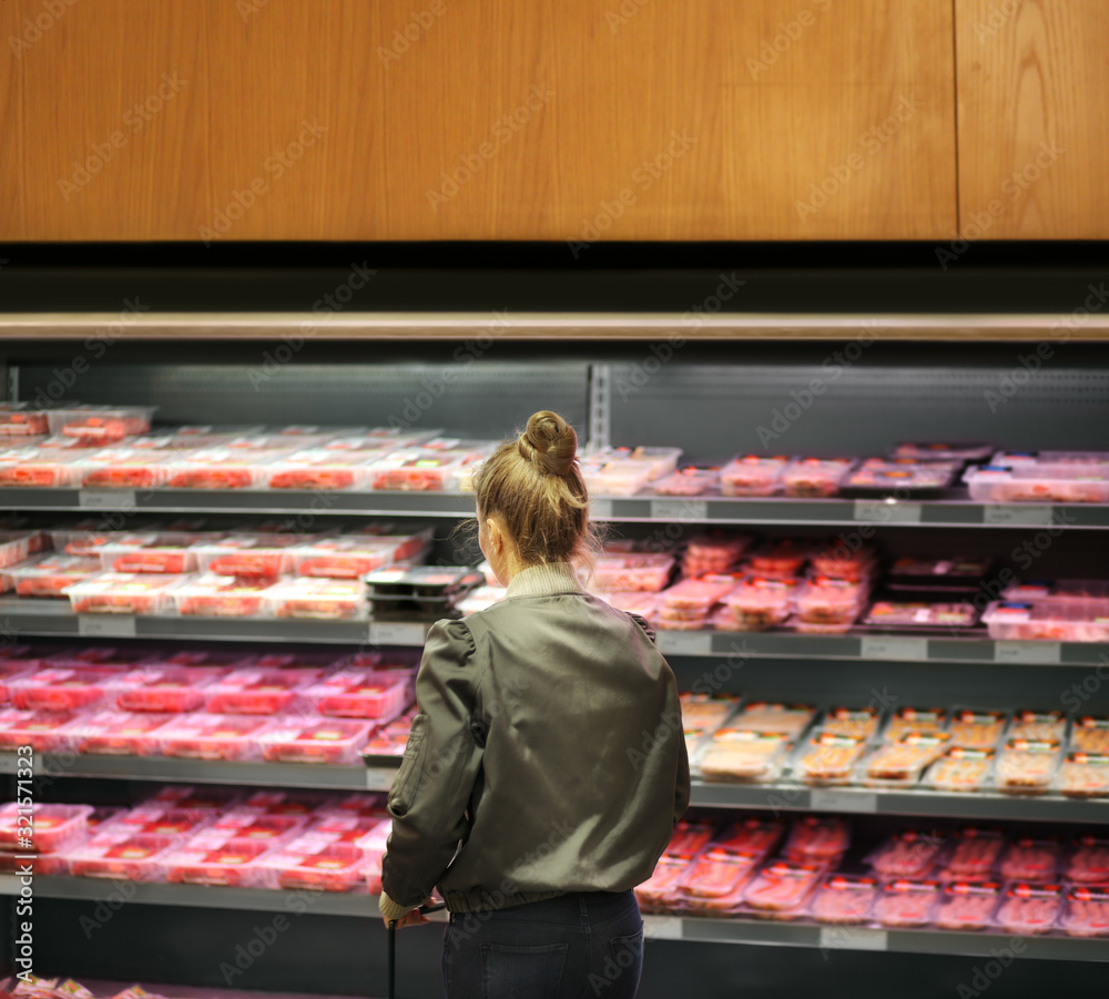 Woman purchasing a packet of meat at the supermarket	