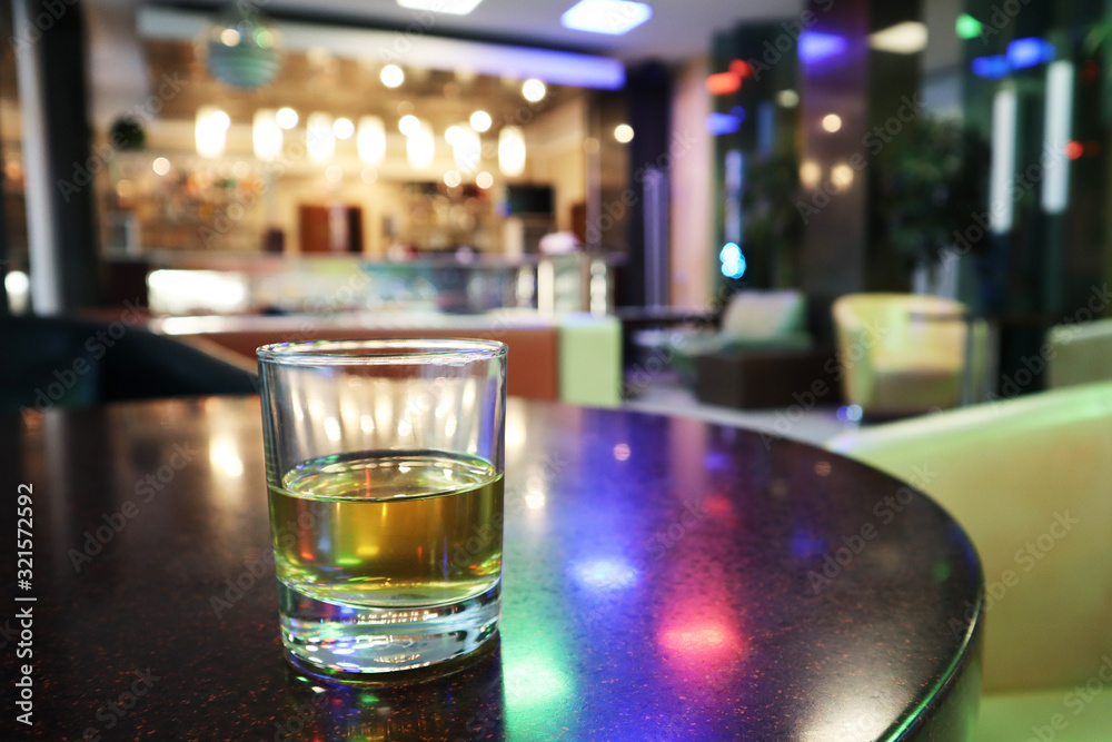 A glass of juice stands on a table in a bar. A glass of juice stands on a table in a bar.