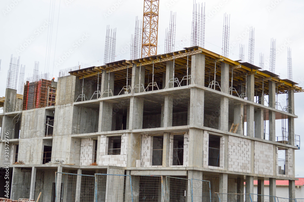 Large concrete cement modern under construction new modern monolithic frame-block house building with windows, walls and balconies