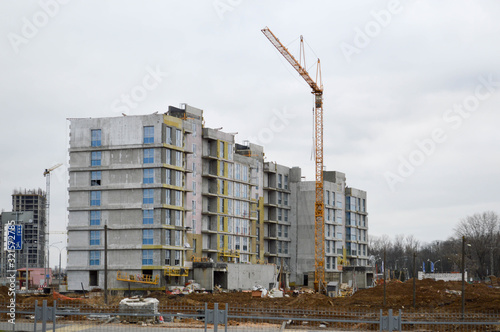 Construction of a new microdistrict with high houses, new buildings with developed infrastructure with the help of large industrial cranes and professional construction equipment in a big city