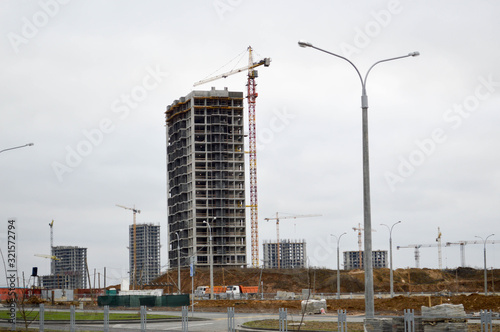 Construction of large modern monolithic frame houses, buildings using industrial construction equipment and large high cranes. Construction of the building in the new micro district of the city