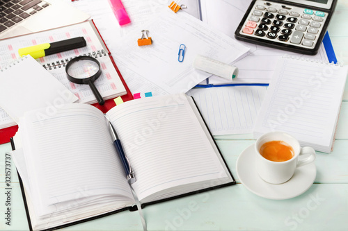 Work with documents. Notebook, pen, notebook, calculator,laptop, financial documents, a cup of cappuccino coffee on the table. Light background.