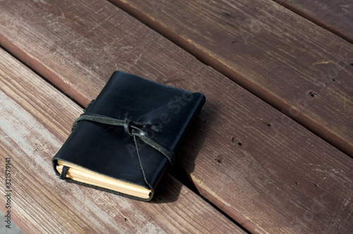 A closed leather bound black journal outdoors on table, wrapped with cord  with copy space. photo