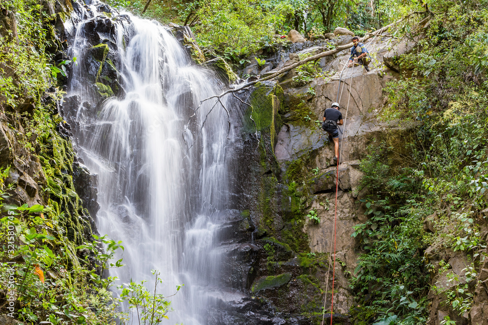 Naklejka premium rappelling down a waterfall