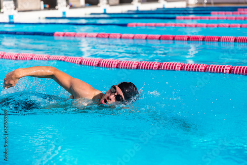 Swimmer man sport training at swimming pool. Professional male athlete doing crawl freestyle stroke technique.