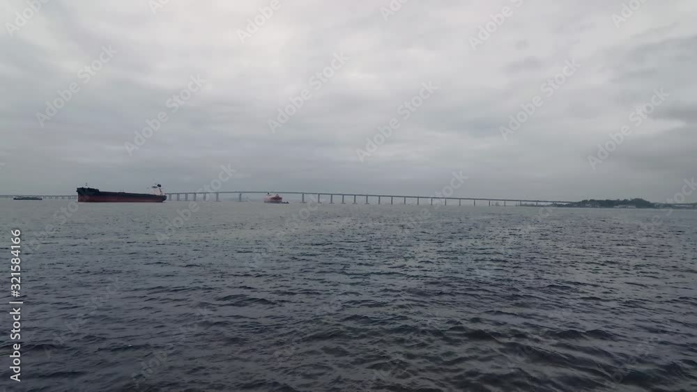 Landscape with the Rio-Niteroi bridge on the horizon, seen through the aquatic transportation window, while crossing the Guanabara Bay, on arrival in Rio de Janeiro City. Landscape with the Rio-Niteroi bridge on the horizon, seen through the aquatic transportation window, while crossing the Guanabara Bay, on arrival in Rio de Janeiro City.