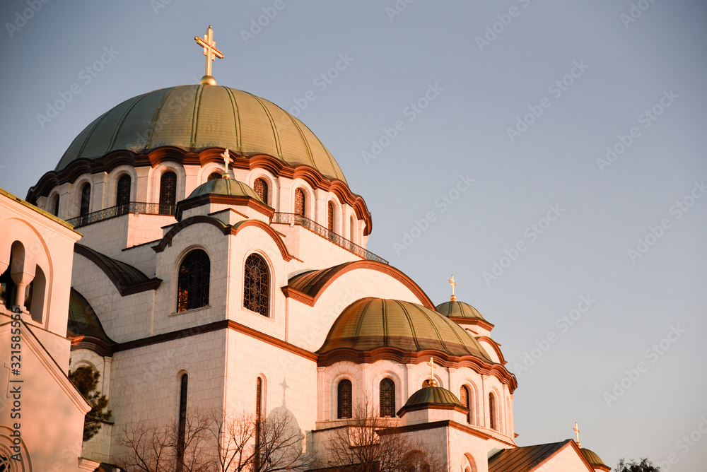 Temple of St. Sava in Belgrade during the warm winter sunset positioned in the lower left part and with negative space in the upper right part of the frame